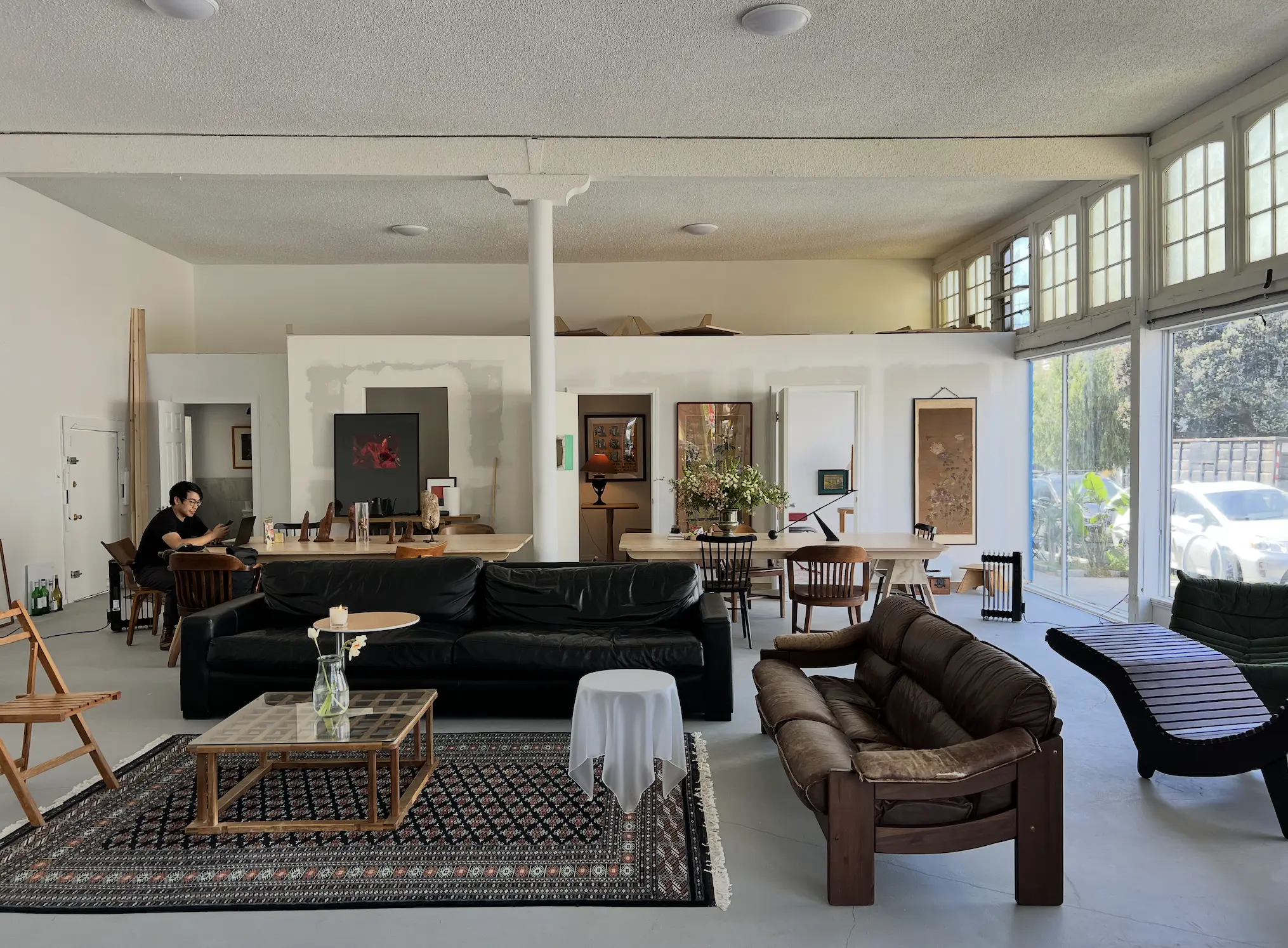 The Interact Studio interior &mdash; a light-filled lounge with sofas, a patterned rug, and artwork on the walls.